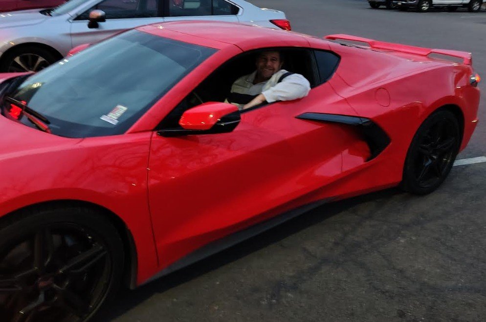 Author test-driving a red Corvette during a vacation, reflecting on financial independence rather than ownership.